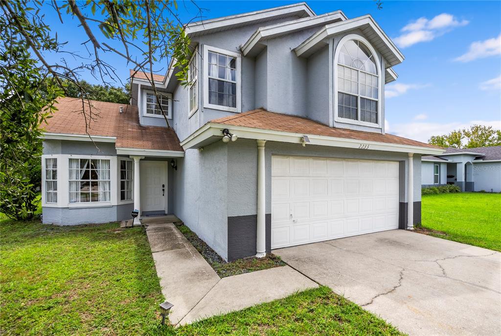 A two-story house with a gray stucco exterior, a white garage door, and a shingled roof — 2233 ARDON AVENUE, ORLANDO, FL