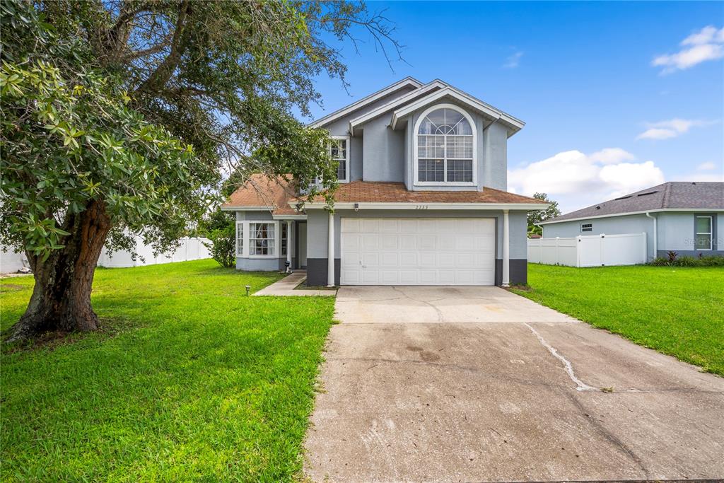 A two-story house with a white garage door, gray siding, and a concrete driveway — 2233 ARDON AVENUE, ORLANDO, FL
