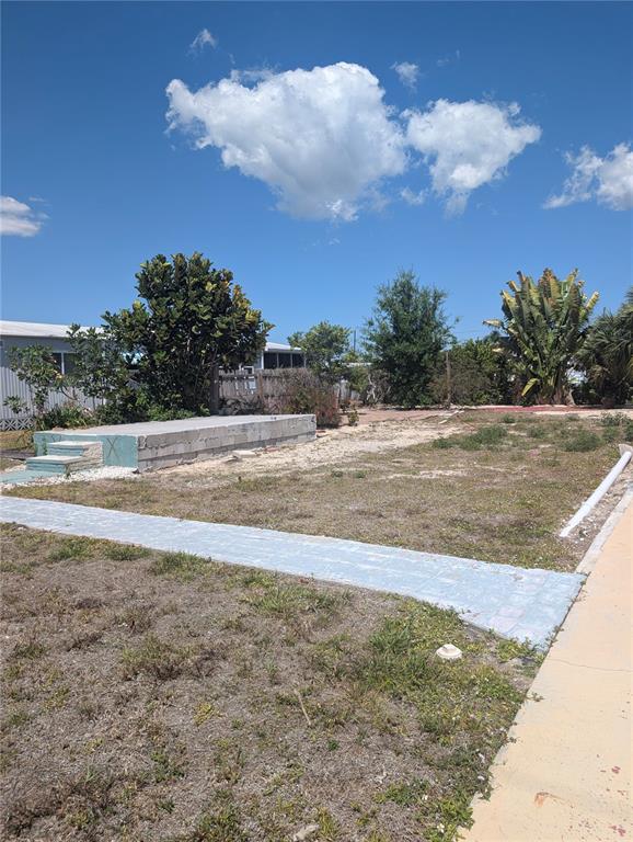 A vacant lot features a concrete foundation slab, a paved walkway, and various trees — 1273 KINGFISHER DRIVE, ENGLEWOOD, FL