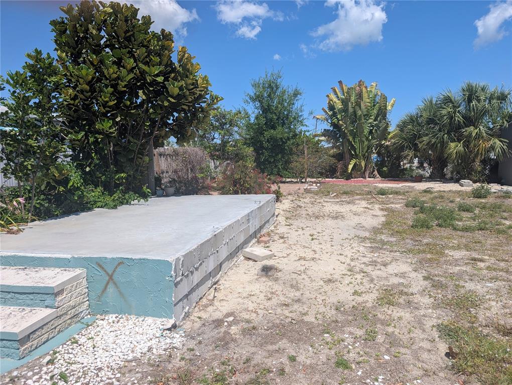 A concrete slab foundation sits in a yard with trees and sparse vegetation — 1273 KINGFISHER DRIVE, ENGLEWOOD, FL
