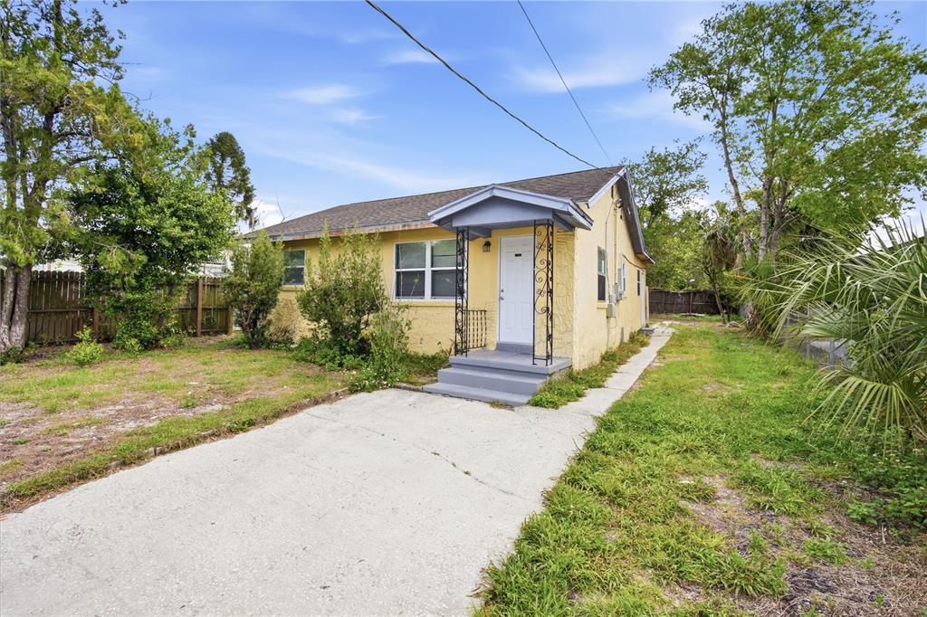 A yellow single-story house with a concrete driveway and a small covered front porch — 8419 N SEMMES STREET, TAMPA, FL