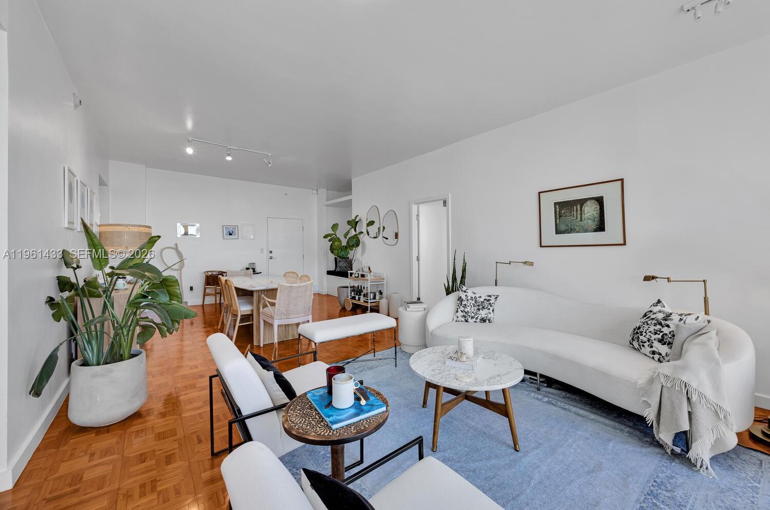 A bright living and dining area features white walls, hardwood floors, and modern furniture — 90 Edgewater Dr, Coral Gables FL 33133, CORAL GABLES, FL