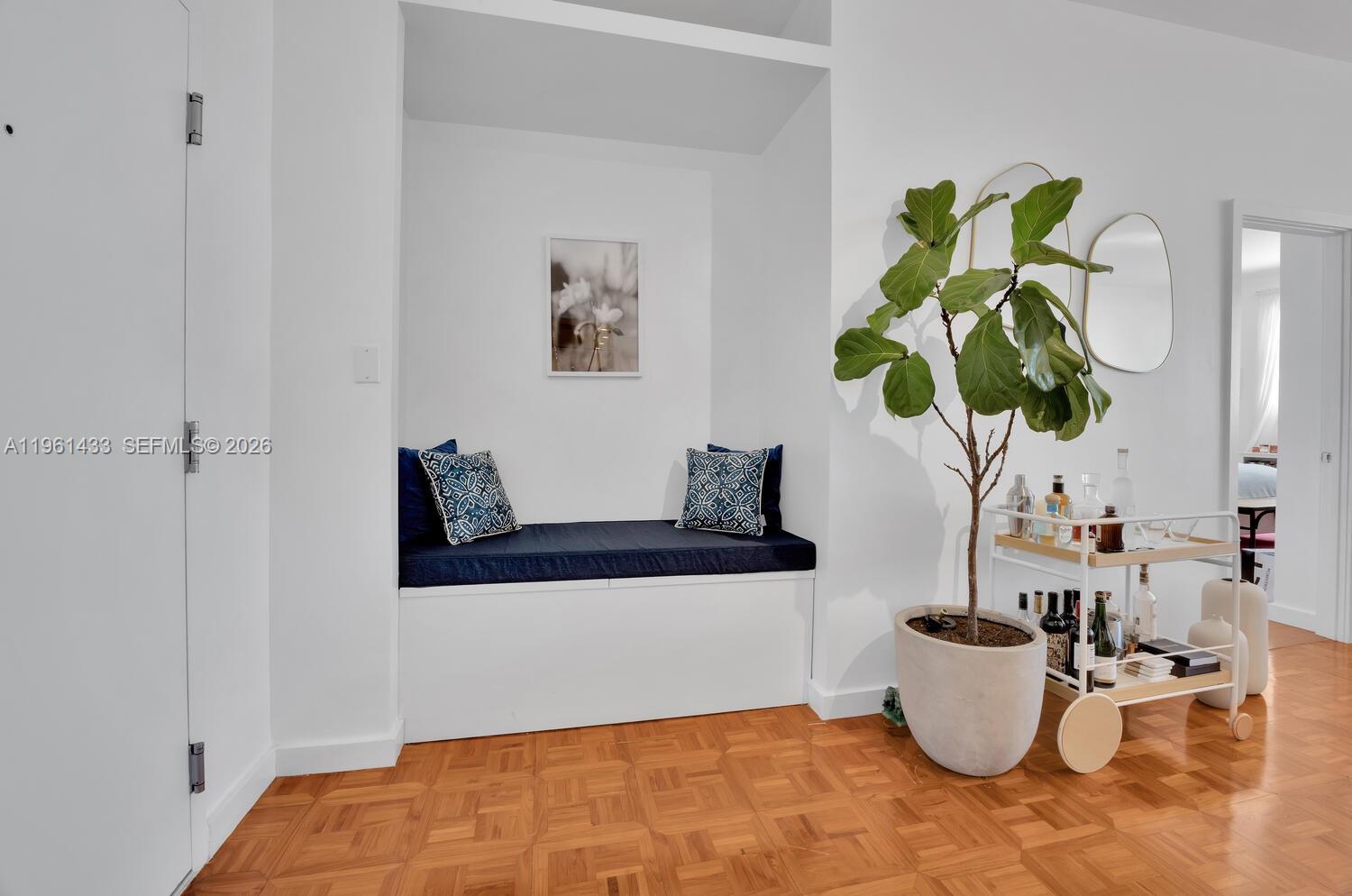 A white built-in bench with blue cushions sits beside a potted plant and bar cart — 90 Edgewater Dr, Coral Gables FL 33133, CORAL GABLES, FL