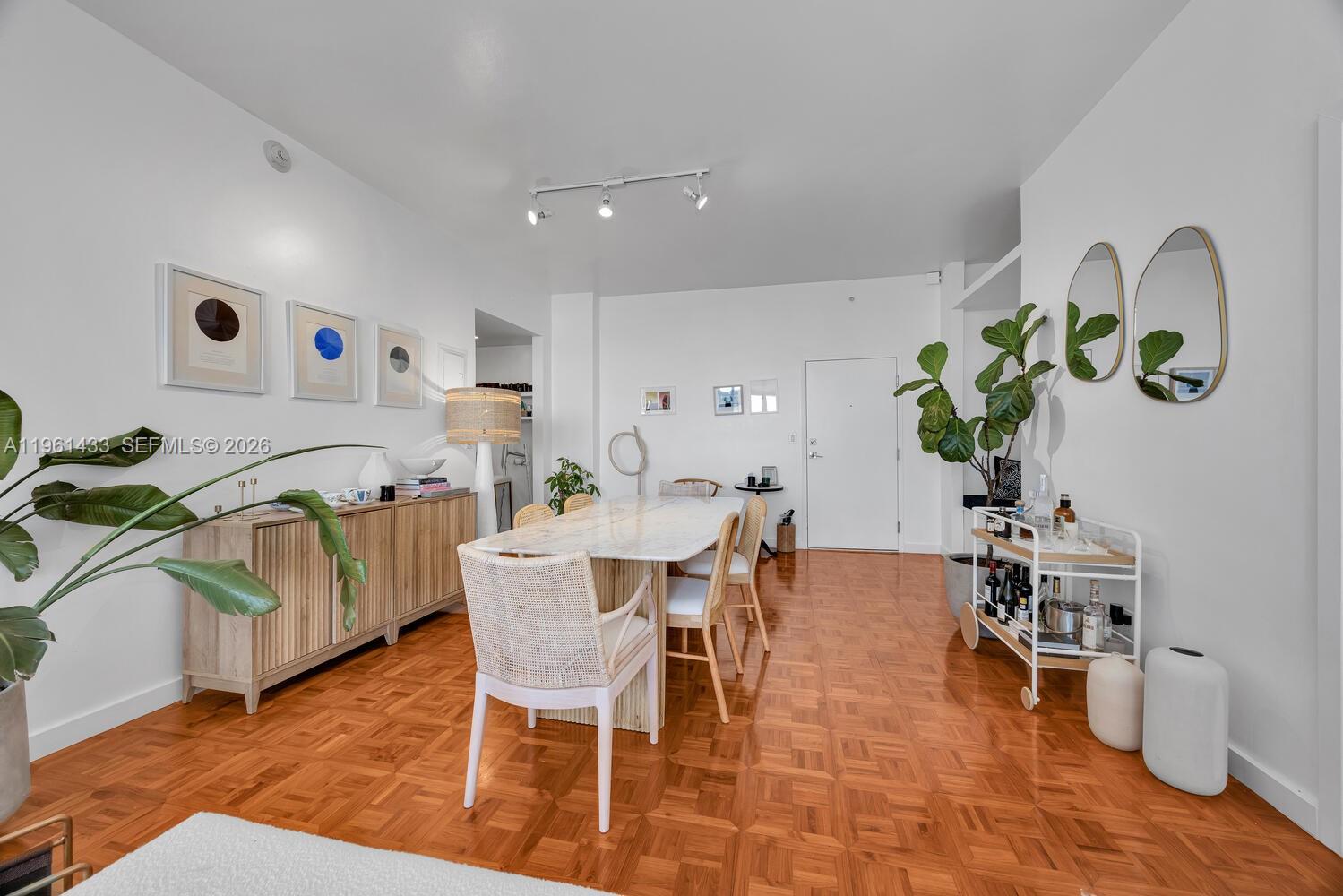 A dining room features a marble table, cane chairs, wood flooring, and a bar cart — 90 Edgewater Dr, Coral Gables FL 33133, CORAL GABLES, FL