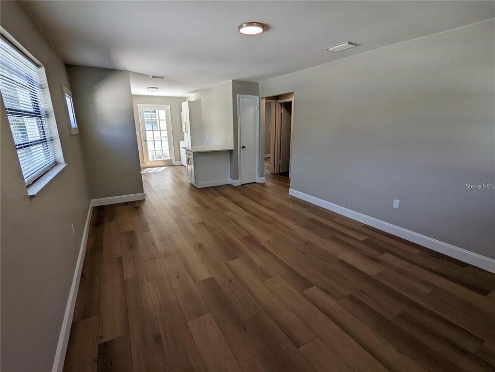 An open-concept living area features wood-look flooring, gray walls, and a view toward the kitchen — 1920/1922 SPRINGTIME AVENUE, CLEARWATER, FL