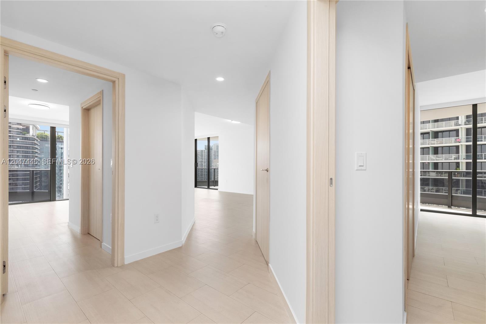 A bright hallway with light wood-look tile floors connects several rooms with modern interior doors — 1000 Brickell Plz # 4015, Miami FL 33131, MIAMI, FL
