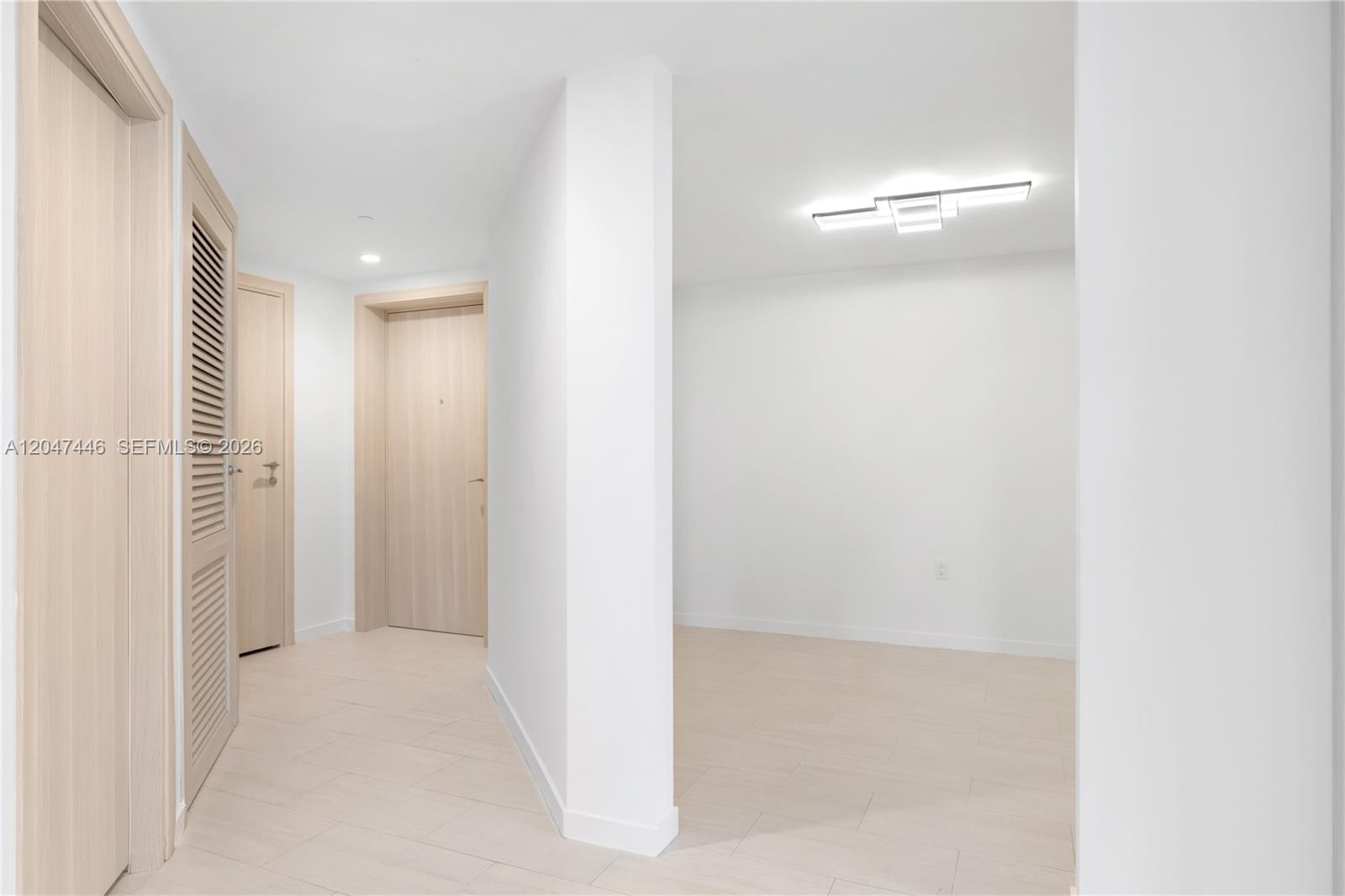 A hallway with light wood doors and flooring leads to an open white room — 1000 Brickell Plz # 4015, Miami FL 33131, MIAMI, FL