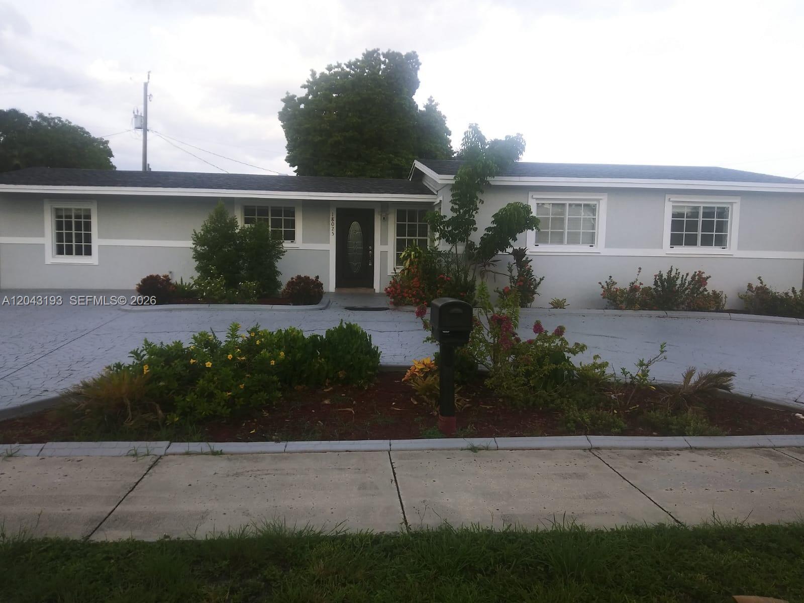 A single-story house with a gray exterior, a paved driveway, and a front garden — 18025 NW 83rd Ave # 1, Hialeah FL 33015, HIALEAH, FL