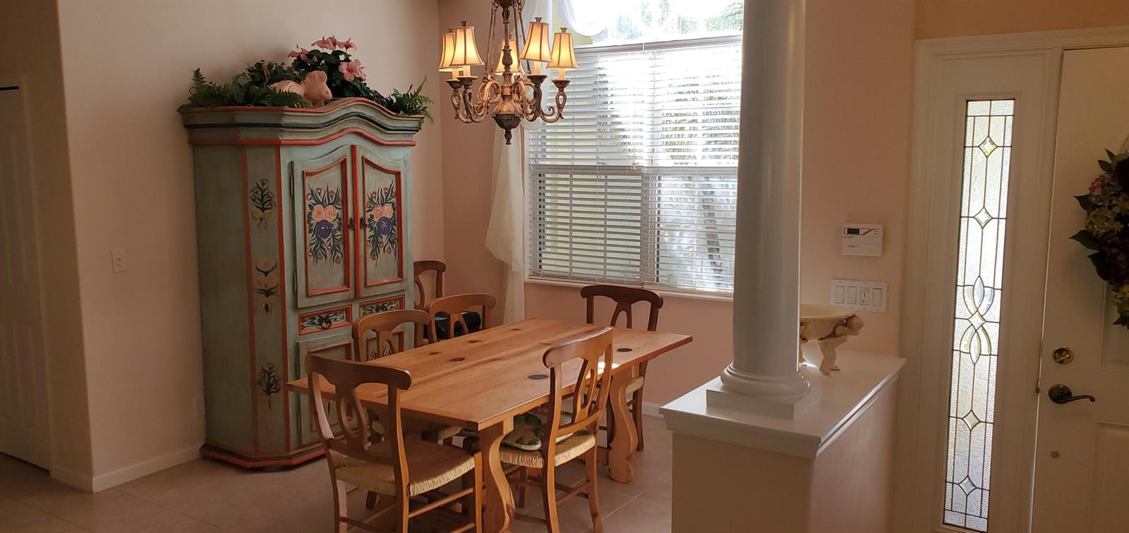 A dining area features a wooden table, chairs, a decorative armoire, and a chandelier — 1128 NW Mossy Oak Way, Jensen Beach FL 34957, JENSEN BEACH, FL