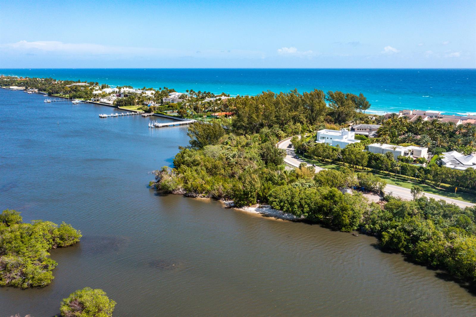 An aerial view shows a coastal landscape with a waterway, lush vegetation, and residential homes — 1980 S Ocean Boulevard, Palm Beach FL 33480, PALM BEACH, FL