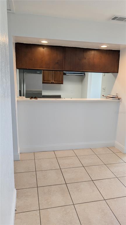 A kitchen pass-through window with dark wood cabinets overlooks a tiled dining area — 4028 BILLINGSGATE RD, ORLANDO, FL