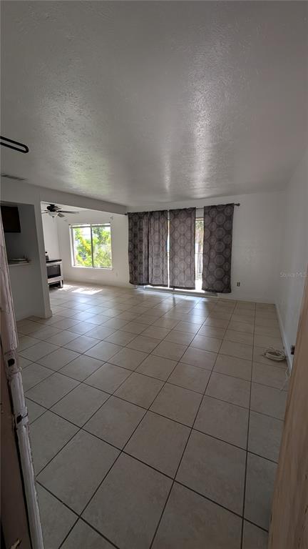 An open-concept living area features light-colored tile flooring, a kitchen, and sliding glass doors — 4028 BILLINGSGATE RD, ORLANDO, FL