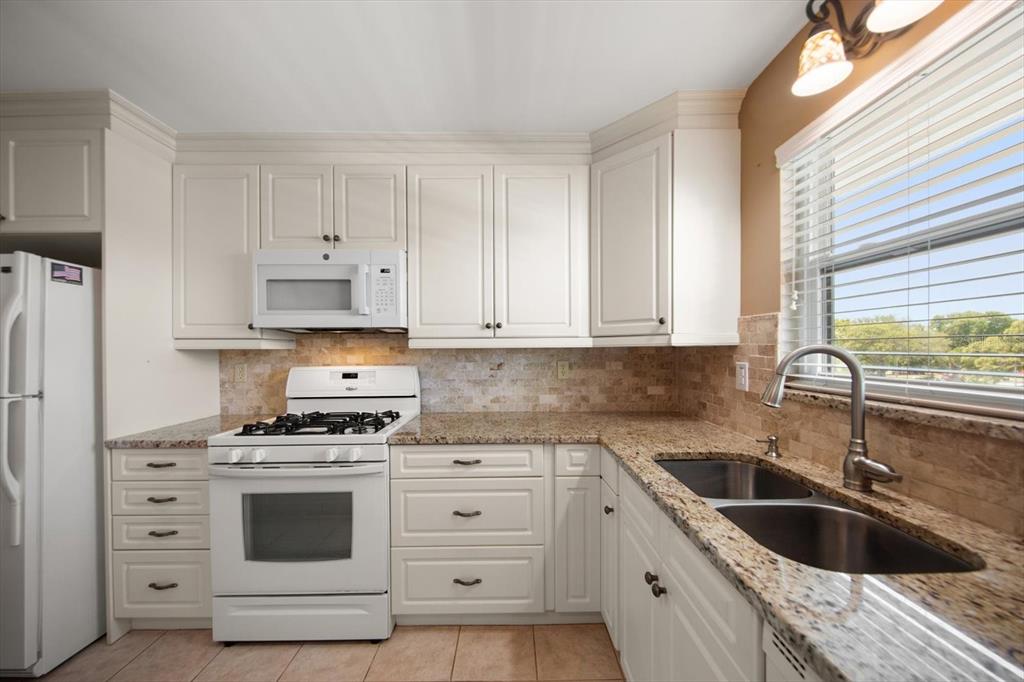 A kitchen with white cabinets, granite countertops, a gas range, and a stainless steel sink — 5970 80TH STREET N UNIT 411, ST PETERSBURG, FL
