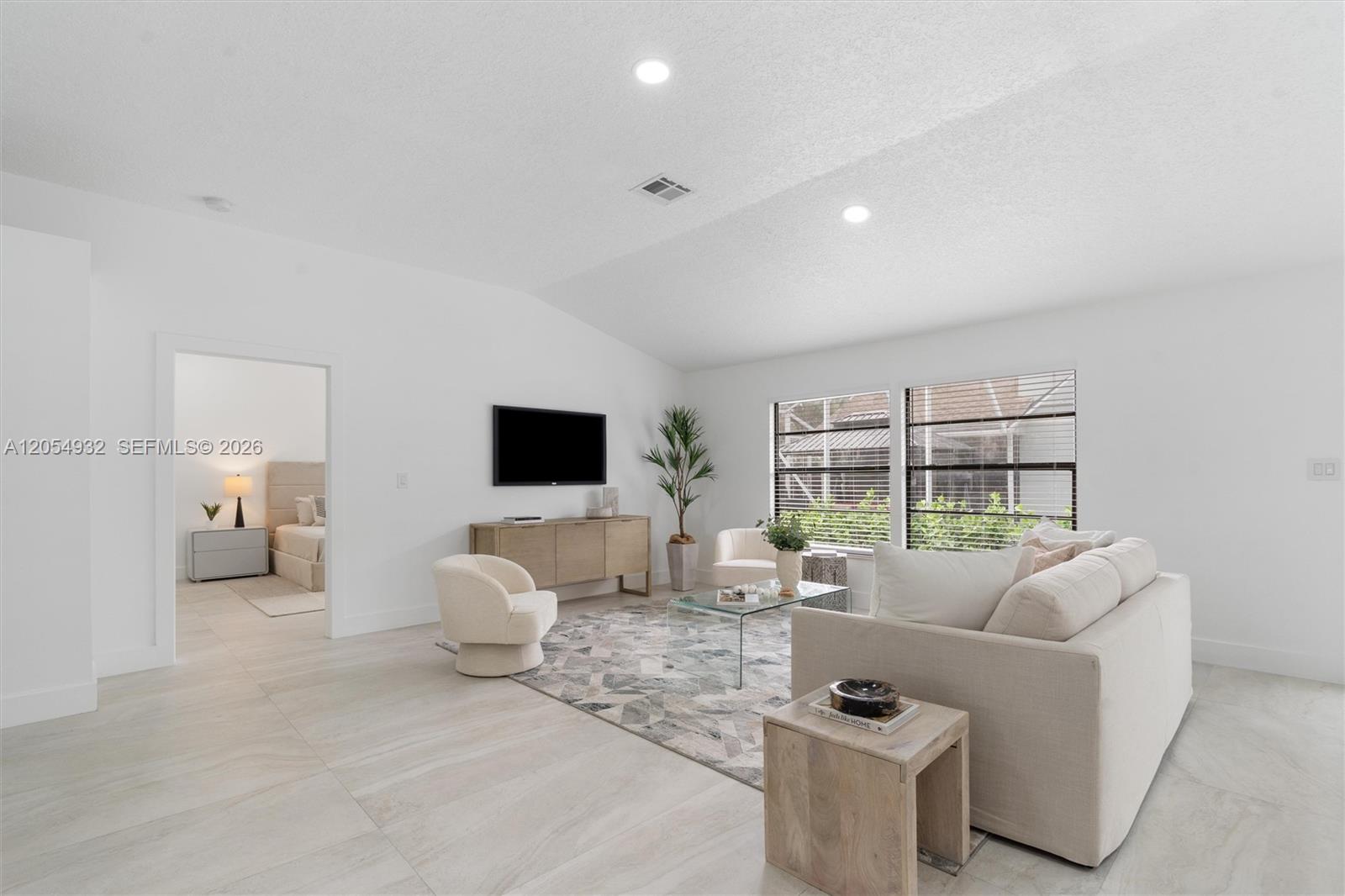 A bright living room features white walls, tile flooring, a sofa, and two armchairs — 1665 Weather Vane Pl, Wellington FL 33414, WELLINGTON, FL