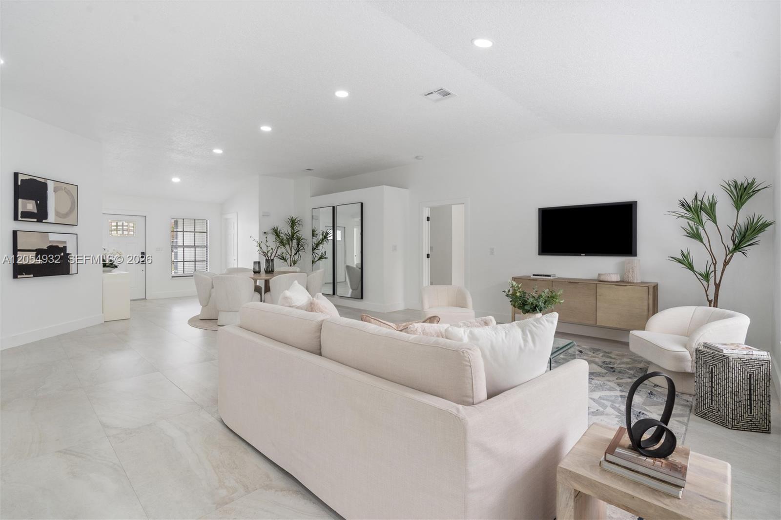 A bright, open-concept living and dining area features white walls, tile flooring, and modern furniture — 1665 Weather Vane Pl, Wellington FL 33414, WELLINGTON, FL