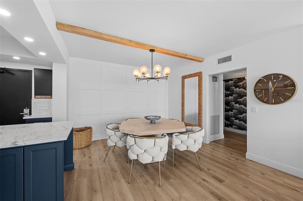 A dining area features a hexagonal table, white tufted chairs, and a wooden ceiling beam — 7100 SUNSHINE SKYWAY LANE S UNIT 701, ST PETERSBURG, FL