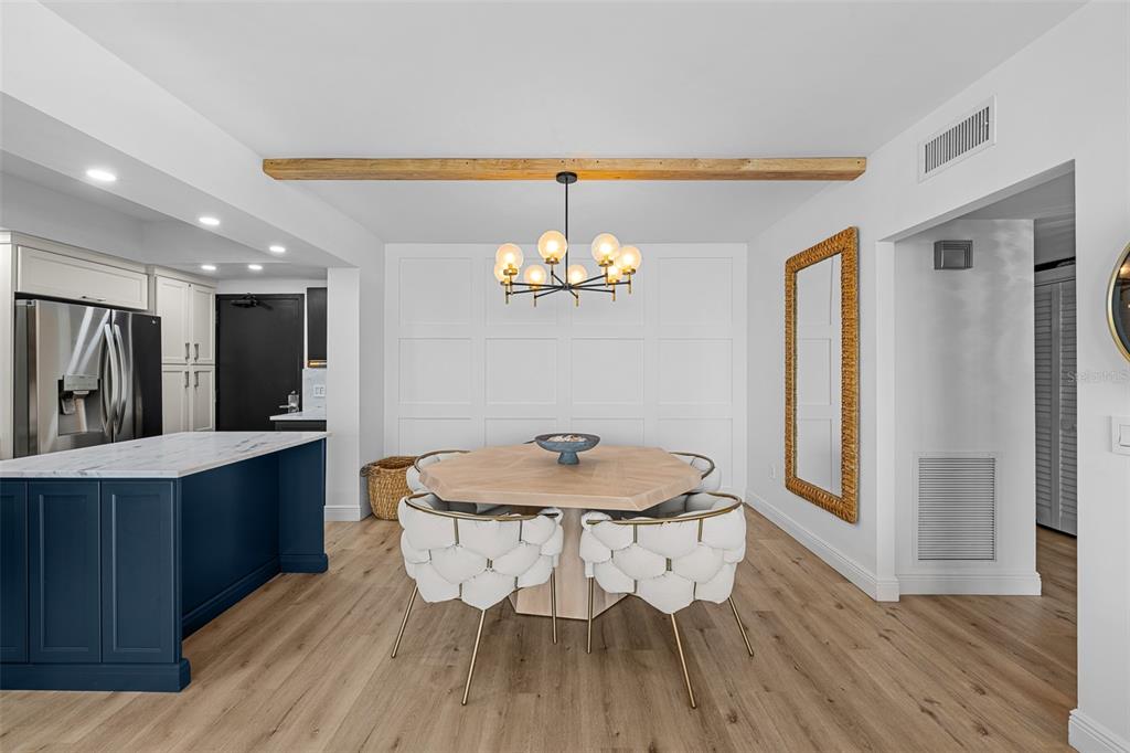 A dining area features a wooden table, white tufted chairs, and a modern chandelier — 7100 SUNSHINE SKYWAY LANE S UNIT 701, ST PETERSBURG, FL