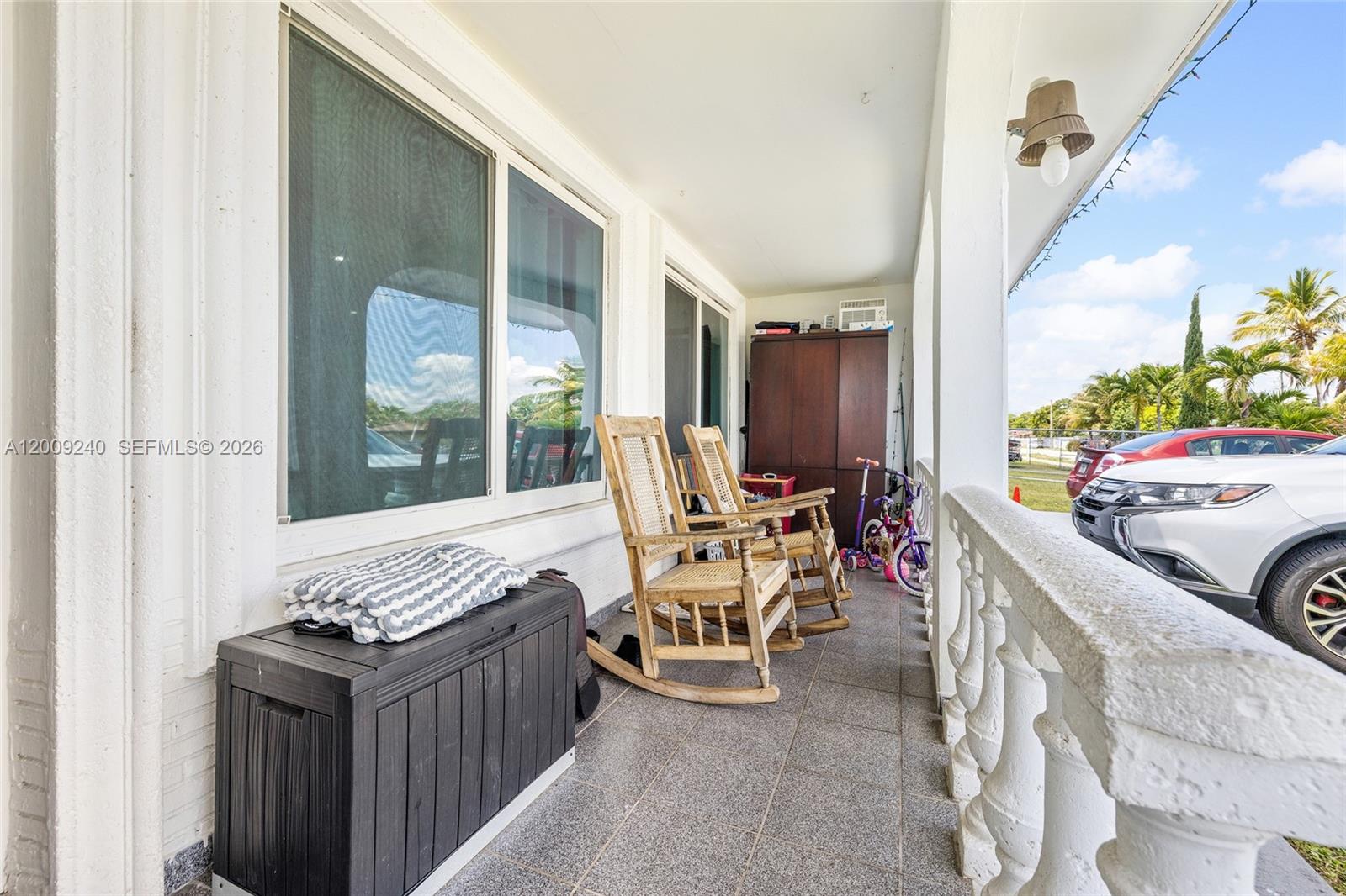 A covered porch features two wooden rocking chairs, a storage chest, and a white railing — 11810 SW 172nd St, Miami FL 33177, MIAMI, FL
