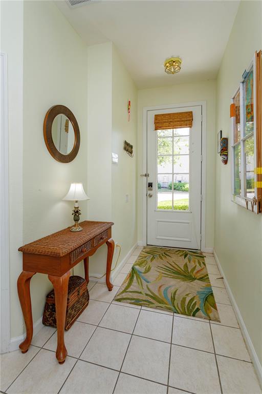 An entryway features a tiled floor, a wooden console table, a round mirror, and a door — 2348 SILVER PALM DRIVE, KISSIMMEE, FL