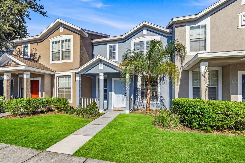 A blue two-story townhouse with a front porch, a small palm tree, and green landscaping — 515 SWEET HOLLOW PLACE, BRANDON, FL