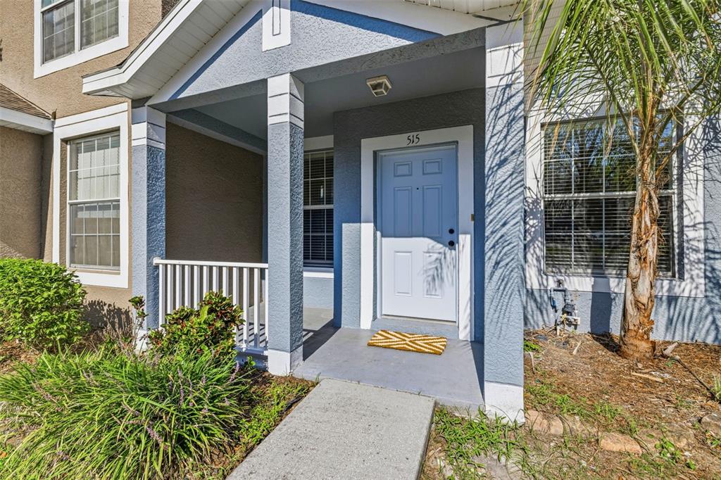 The exterior of a blue house features a covered front porch and a light blue door — 515 SWEET HOLLOW PLACE, BRANDON, FL