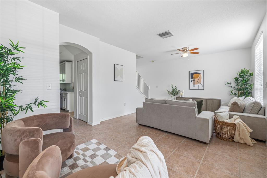 A living room with tile flooring, a beige sofa, and an arched doorway to the kitchen — 515 SWEET HOLLOW PLACE, BRANDON, FL