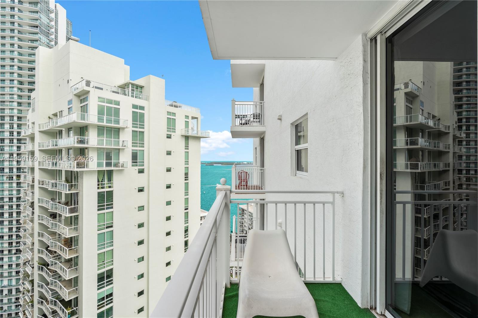 A balcony with a white lounge chair overlooks a bay between two high-rise buildings — 185 SE 14th Ter # 2602, Miami FL 33131, MIAMI, FL