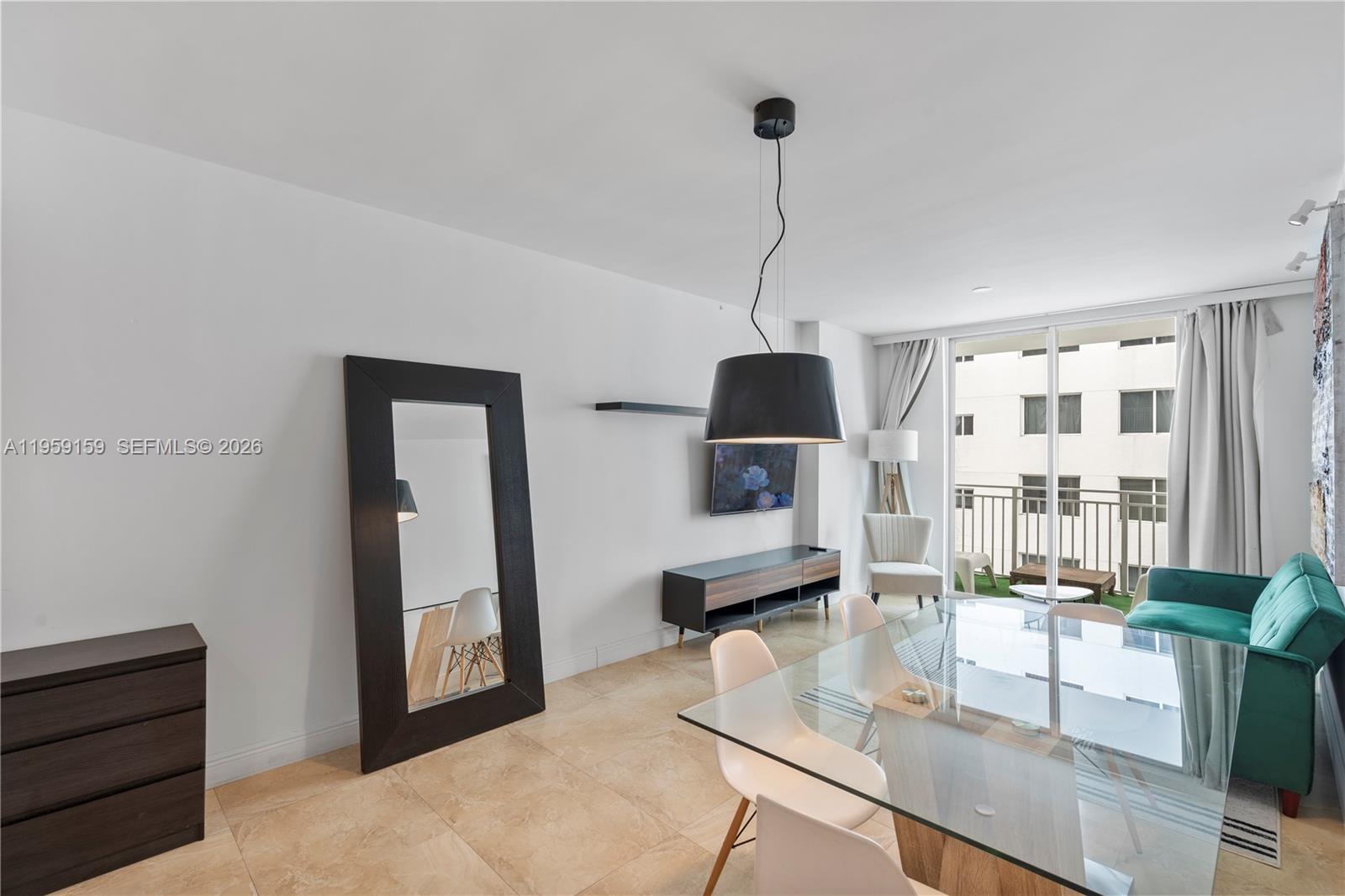 A modern living and dining area features a glass table, green sofa, and large mirror — 185 SE 14th Ter # 2602, Miami FL 33131, MIAMI, FL