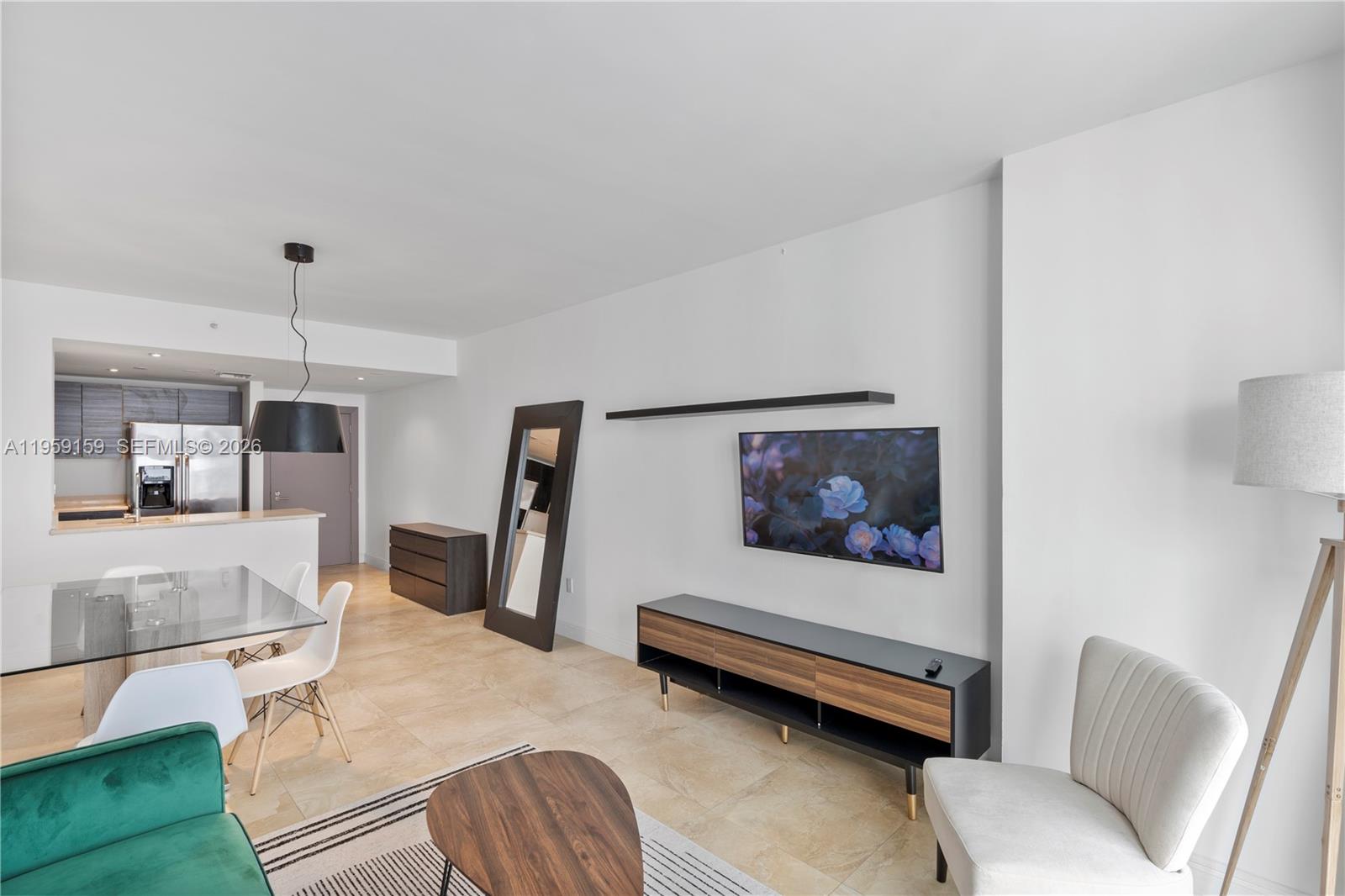 A modern living room features a wall-mounted television, a media console, and a dining area — 185 SE 14th Ter # 2602, Miami FL 33131, MIAMI, FL