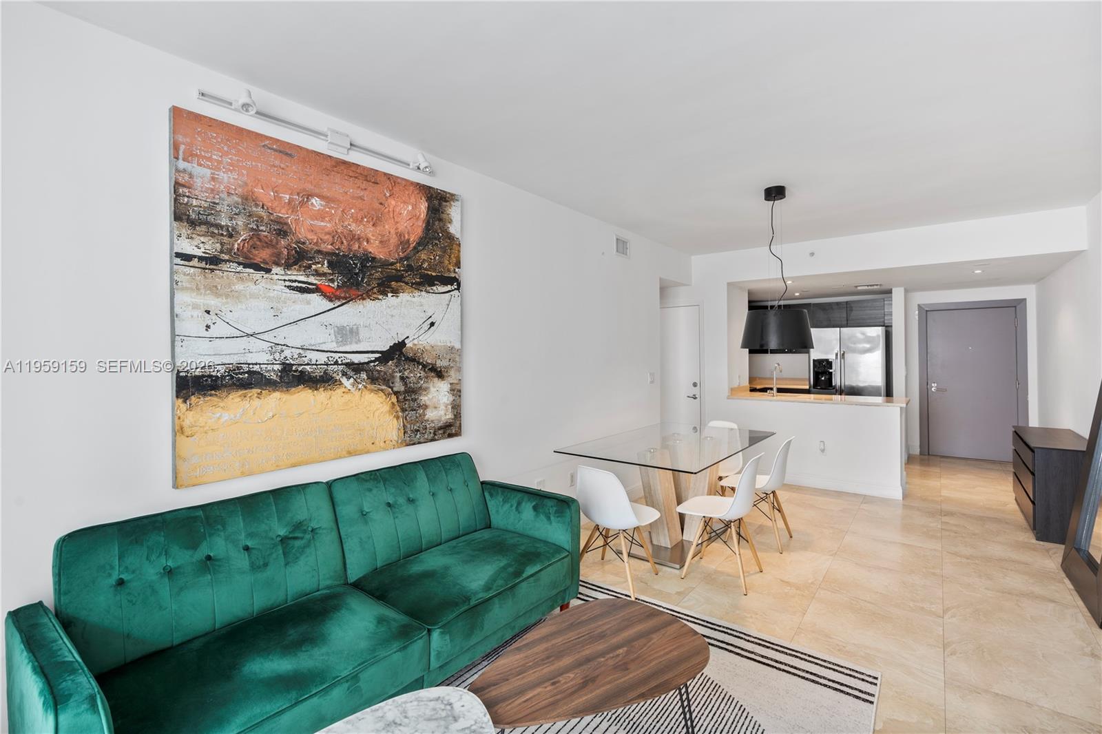 A living and dining area features a green sofa, glass table, and abstract wall art — 185 SE 14th Ter # 2602, Miami FL 33131, MIAMI, FL