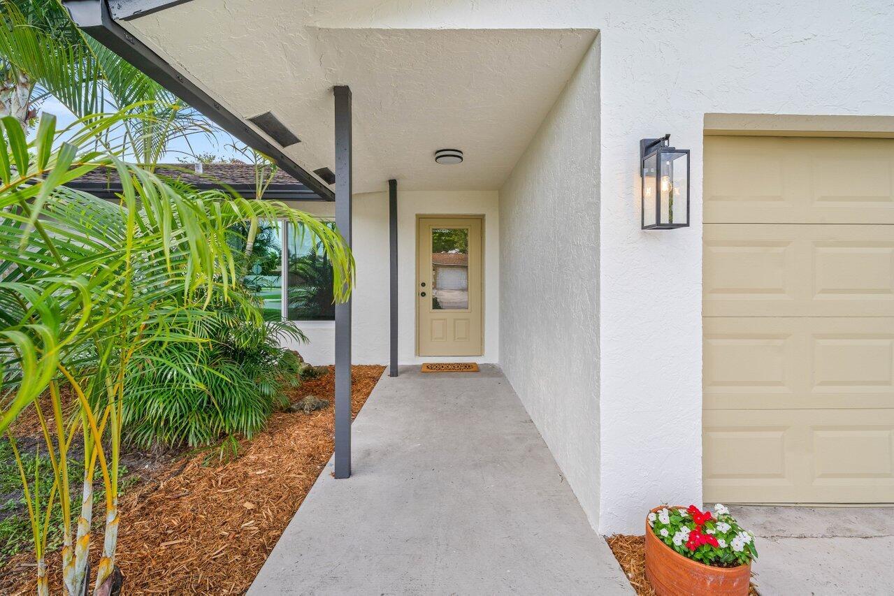 A concrete walkway leads to a tan front door under a covered entryway — 638 SW 4th Avenue, Boynton Beach FL 33426, BOYNTON BEACH, FL