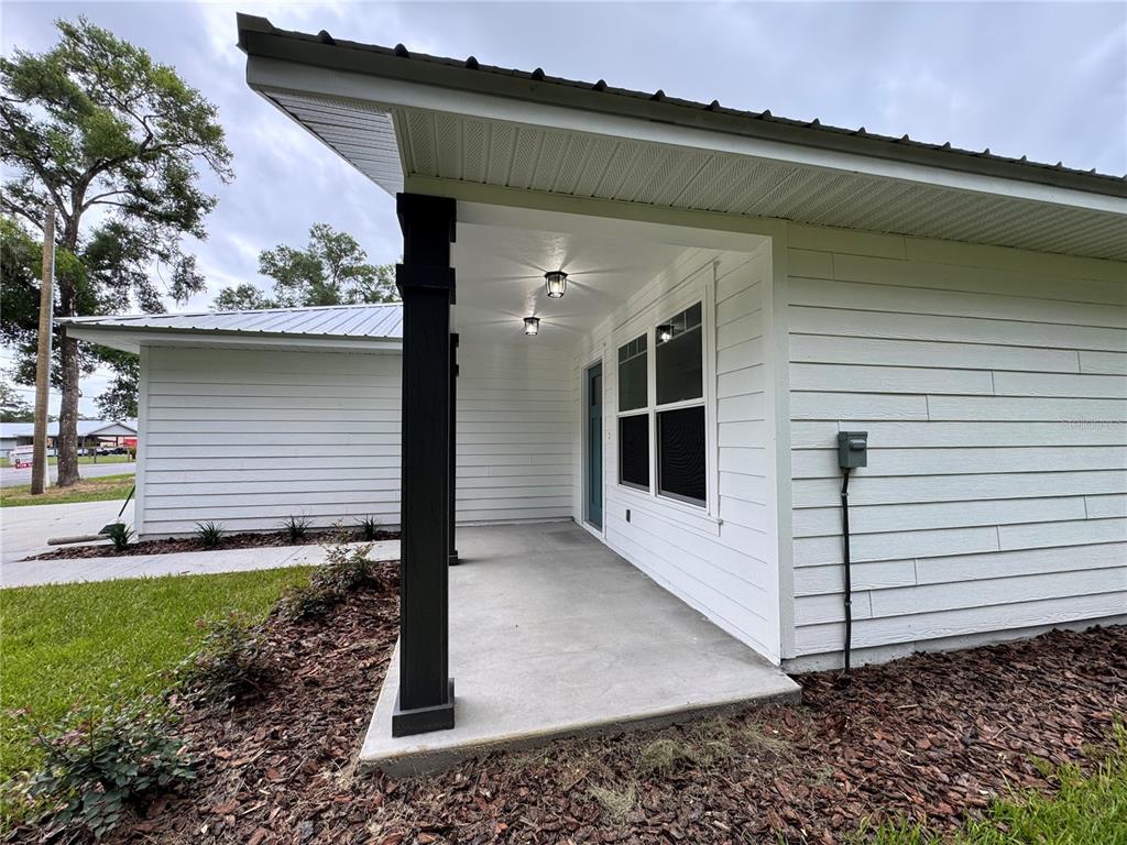 A covered concrete porch features a black support pillar and white horizontal siding — 8507 SE 70TH AVENUE, TRENTON, FL