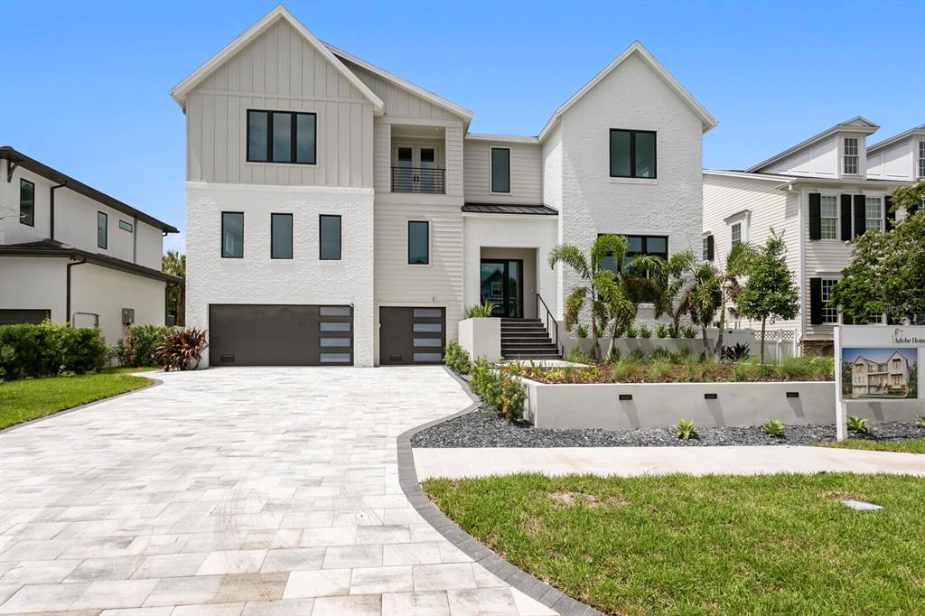 A modern two-story house with a white brick facade, gray siding, and a paved driveway — 5023 W DANTE AVENUE, TAMPA, FL