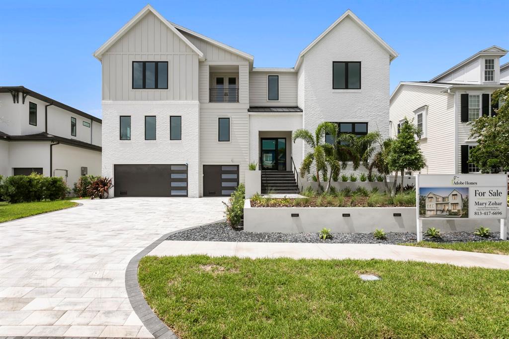 A modern two-story house with a white brick facade, gray siding, and a paved driveway — 5023 W DANTE AVENUE, TAMPA, FL