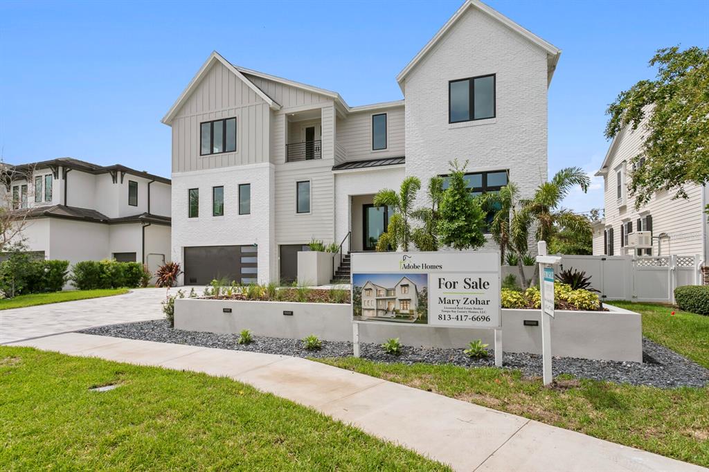 A modern two-story house with white brick and gray siding features a front yard sign — 5023 W DANTE AVENUE, TAMPA, FL