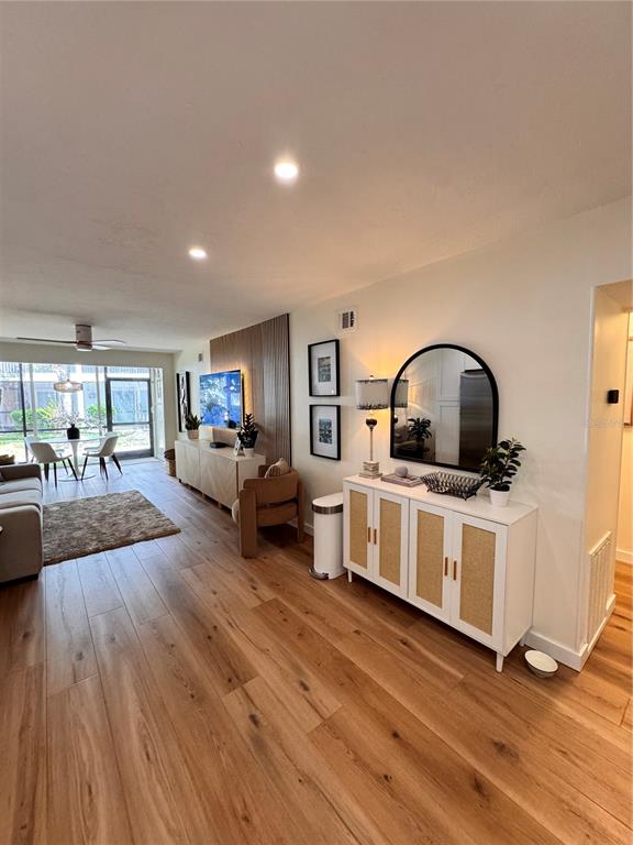 A living room features light wood flooring, a white cabinet with rattan doors, and a mirror — 5623 MIDNIGHT PASS ROAD UNIT 615, SIESTA KEY, FL