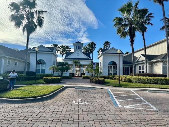 A paved parking area leads to a community clubhouse with palm trees and white siding — 330 SOUTHERN PECAN CIRCLE UNIT 208, WINTER GARDEN, FL