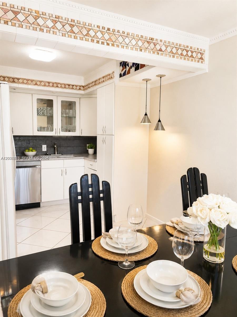 A dining area with a black table and chairs sits adjacent to a white kitchen — 2050 Newcastle C # 2050, Boca Raton FL 33434, BOCA RATON, FL