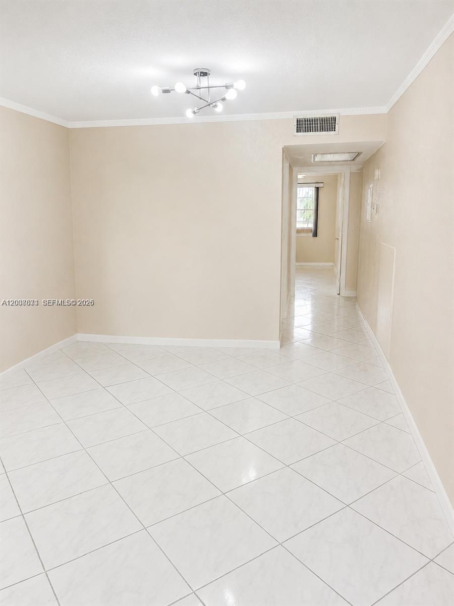 A room with light-colored tile flooring, beige walls, and a modern multi-bulb ceiling light — 2050 Newcastle C # 2050, Boca Raton FL 33434, BOCA RATON, FL
