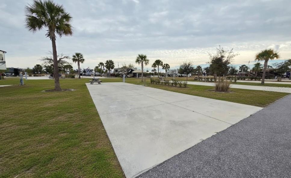 A concrete RV pad sits on a grassy lot with palm trees under a cloudy sky — 103 HIGHWAY 630 E, LAKE WALES, FL