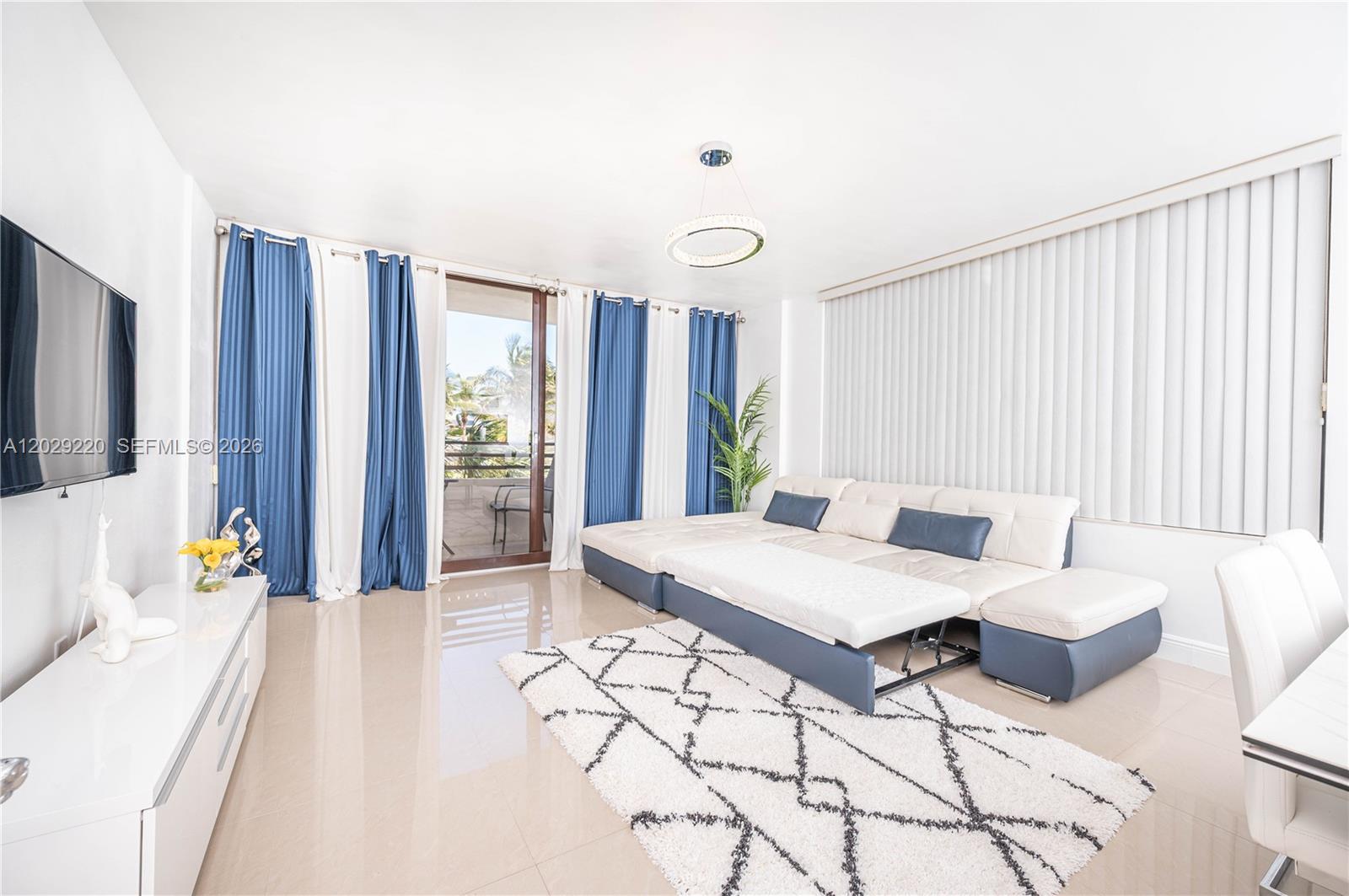 A living room features a white sectional sofa, a patterned rug, and blue curtains — 3505 S Ocean Dr # 221, Hollywood FL 33019, HOLLYWOOD, FL