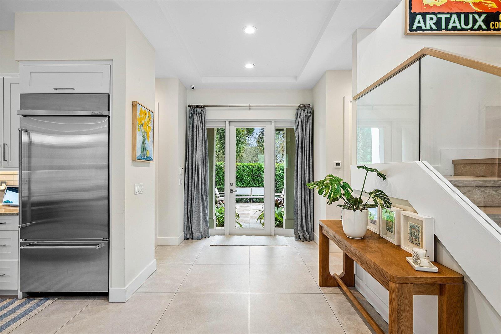 A bright entryway features a stainless steel refrigerator, a wooden console table, and glass doors — 217 Gulfstream Boulevard, Boynton Beach FL 33435, BOYNTON BEACH, FL