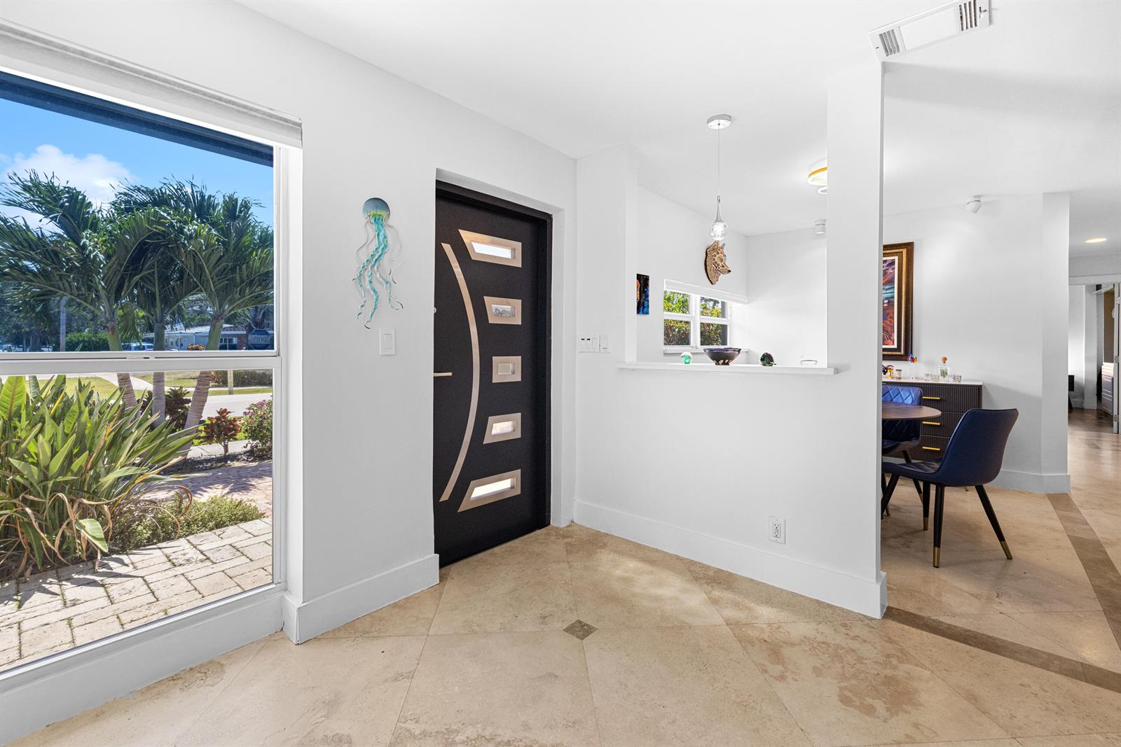 An entryway features a dark modern door, tiled floors, and a view of palm trees — 5041 NE 24th Avenue, Lighthouse Point FL 33064, LIGHTHOUSE POINT, FL