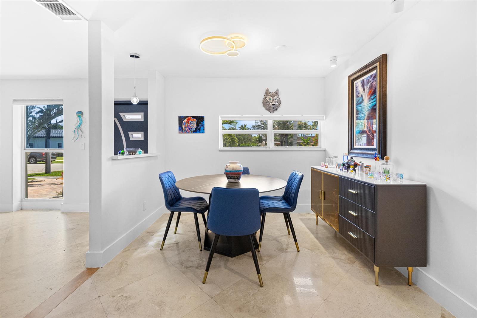 A dining room features a round table, blue chairs, a sideboard, and a window view — 5041 NE 24th Avenue, Lighthouse Point FL 33064, LIGHTHOUSE POINT, FL