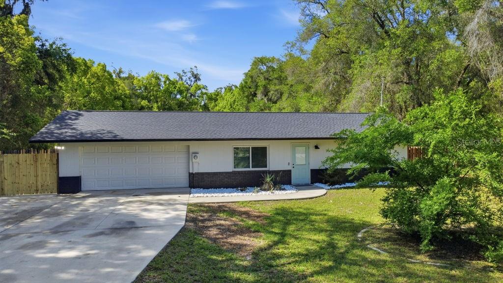 A single-story house with a white exterior, dark brick base, and a light blue front door — 550 E MINNESOTA AVENUE, ORANGE CITY, FL