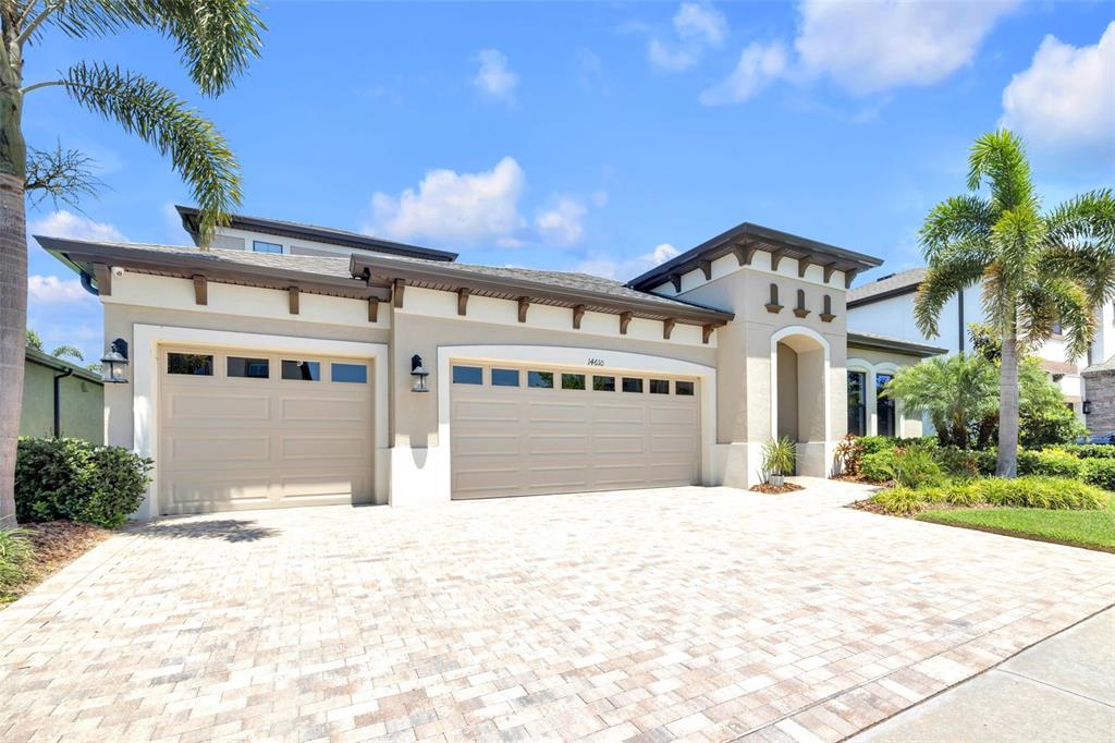 An aerial view of a suburban house with a three-car garage at sunset by water — 14610 RED CASTLE AVE, LITHIA, FL