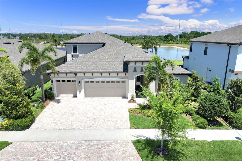 An aerial view shows a suburban house with a paved driveway and a backyard pond — 14610 RED CASTLE AVE, LITHIA, FL