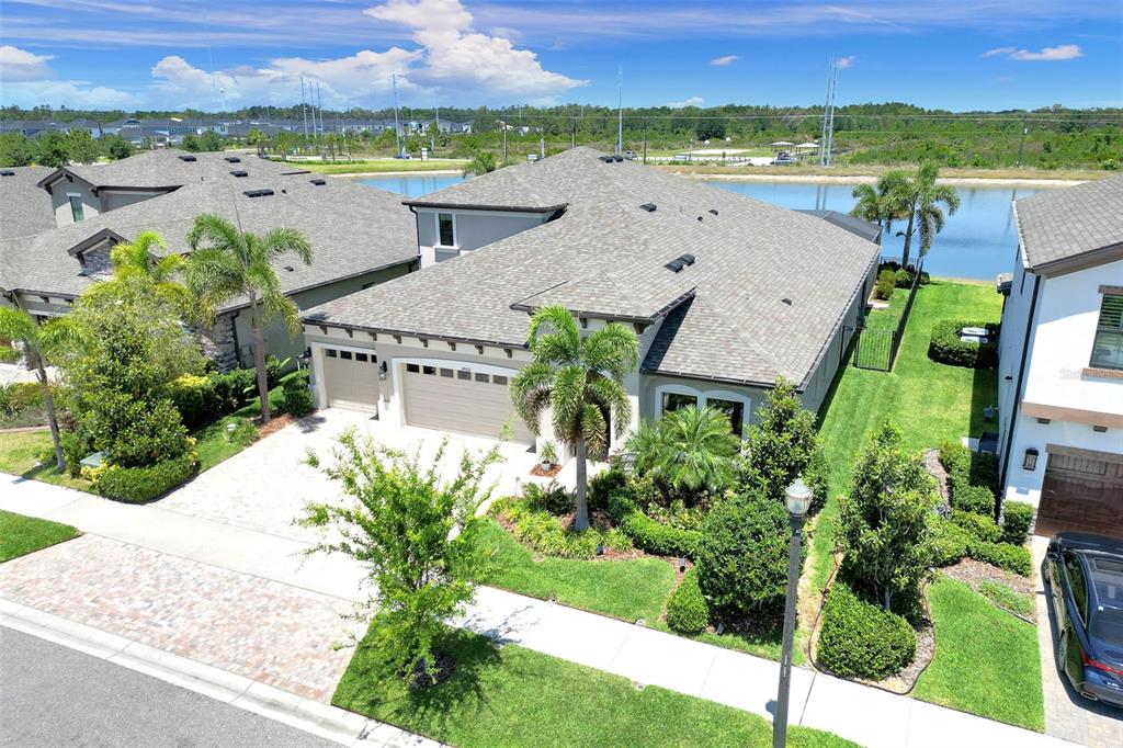 A beige single-story house with a three-car garage, paver driveway, and palm trees — 14610 RED CASTLE AVE, LITHIA, FL
