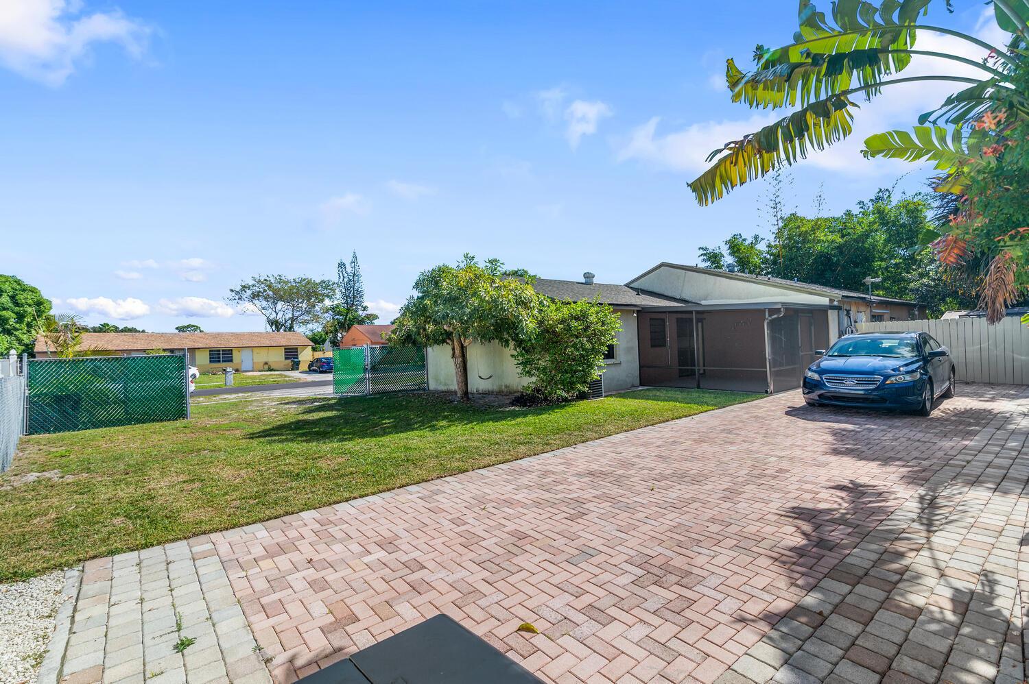 A paved driveway leads to a house with a screened patio and a grassy yard — 4619 Gladiator Circle, FL 33463, FL