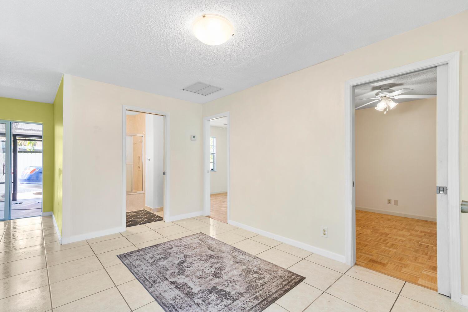 A tiled room with a rug, three doorways, and a view into a bedroom — 4619 Gladiator Circle, FL 33463, FL